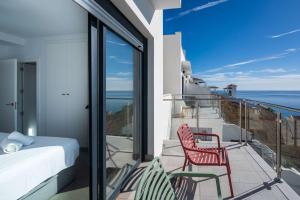 a bedroom with a balcony with a bed and two chairs at Terrazas de Ladera Duplex 7 Casasol in Nerja