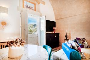 a living room with a glass table and blue chairs at Suite San Pietro - Sassi di Matera in Matera