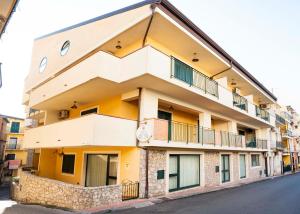 an apartment building with a balcony on a street at Le Tartarughe Aparthotel in Letojanni