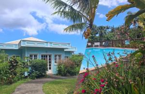 a house with a swimming pool and flowers at Le four à pain in Saint-Philippe