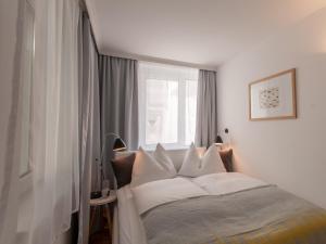 a bedroom with a bed with white sheets and a window at Design Apartment Zell am See in Zell am See