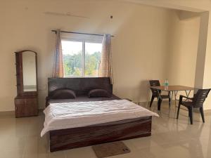 a bedroom with a bed and a table and a window at Laya hotels in Chintāmani