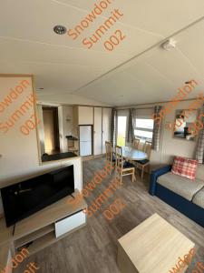 a living room with a tv and a couch and a table at Snowdon Summit 002 in Barmouth