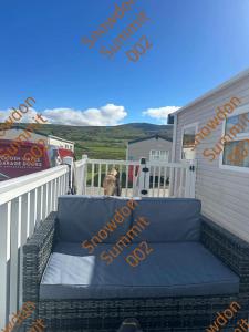 a blue couch sitting on a porch with a dog at Snowdon Summit 002 in Barmouth