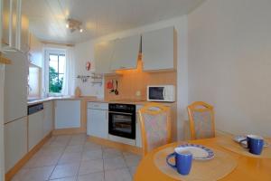 a kitchen with a table and a kitchen with white cabinets at STW24a Bungalow in Dorum-Neufeld