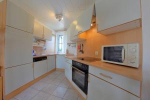 a kitchen with white cabinets and a microwave at STW24a Bungalow in Dorum-Neufeld