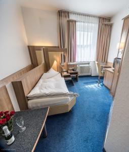 アーヘンにあるホテル ロウスベルクのベッドとデスクが備わるホテルルームです。