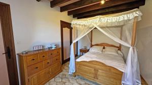 a bedroom with a canopy bed and a wooden dresser at Fayollas in Bussière-Galant