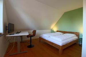 a bedroom with a bed and a desk with a computer at WK7 "Ferienwohnung Küstenruhe" in Dorum