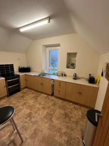 a large kitchen with wooden cabinets and a window at Station apartment in Llanberis