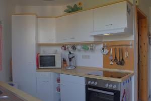 a kitchen with white cabinets and a microwave at STW45b Bungalow Seestern in Dorum-Neufeld