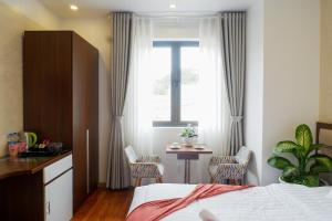 a bedroom with a bed and a table and a window at Tasme Dalat Stay in Da Lat