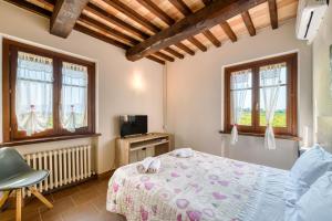 a bedroom with a bed and a tv and windows at Casale Rialto in Montefalco