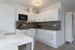 a kitchen with white cabinets and a white table at KW4 Haus Anna in Dorum-Neufeld