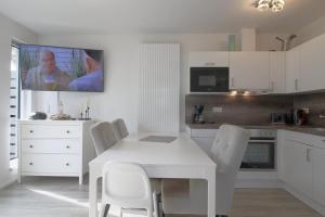 a white kitchen with a white table and chairs at KW4 Haus Anna in Dorum-Neufeld