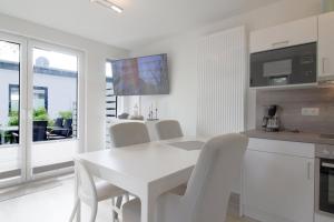 a white dining room with a white table and chairs at KW4 Haus Anna in Dorum-Neufeld +6 photos