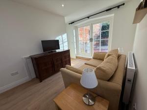 a living room with a couch and a tv at The Coach House in Halstead