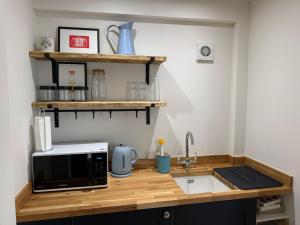 a kitchen counter with a microwave and a sink at The Coach House in Halstead