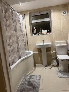 a bathroom with a tub sink and a toilet at London Heathrow Accommodation in Hillingdon