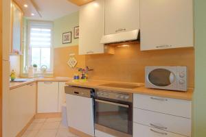 a kitchen with white cabinets and a microwave at LT 33 Bungalow Manu in Dorum-Neufeld