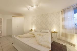 a white bedroom with a bed with two lights on it at LT 33 Bungalow Manu in Dorum-Neufeld