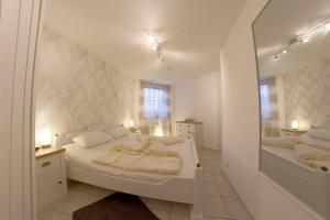 a white bedroom with a bed and a mirror at LT 33 Bungalow Manu in Dorum-Neufeld