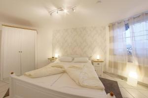 a white bed in a white bedroom with two lights at LT 33 Bungalow Manu in Dorum-Neufeld