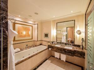 a bathroom with a tub and a large mirror at Grand Hotel Amrâth Kurhaus The Hague Scheveningen in Scheveningen