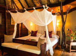 a bedroom with a canopy bed and a couch at Fare PEA ITI Romantic Lodge in Patio