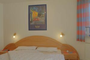 a bed with two pillows and a picture on the wall at LT35 Bungalow Moritz in Dorum-Neufeld