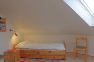 a bedroom with a bed and a chair in a attic at LT35 Bungalow Moritz in Dorum-Neufeld