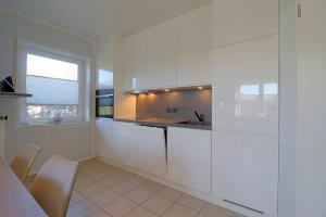 a white kitchen with white cabinets and a window at SI5-01 Terrassenwohnung Deichnah in Cappel-Neufeld