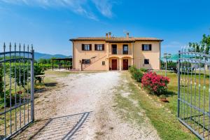a house with a gate in front of a dirt road at Casale Rialto in Montefalco