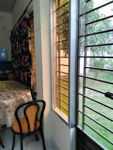 a room with a table and a chair and a window at Mini Banglo in Sylhet