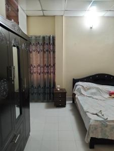 a bedroom with a bed and a dresser and a curtain at Mini Banglo in Sylhet