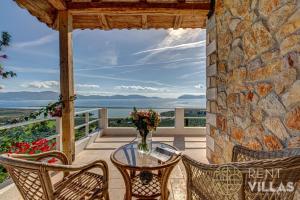 a patio with a glass table and chairs on a balcony at Villa Karima with Sea View in Metókhion
