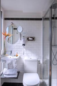 a white toilet sitting next to a shower in a bathroom at Hôtel Villa Bohème in Paris