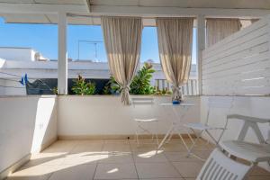 a balcony with chairs and a table and windows at Salaqua Bed and Breakfast in Torre Mozza