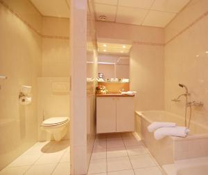 a bathroom with a toilet and a tub and a sink at Hotel Inkelshoes in Epen +18 photos