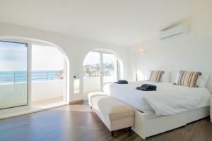 a white bedroom with a white bed and a large window at 14 Travessa das Naus in Carvoeiro +40 photos