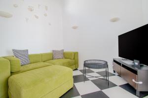 a living room with a green couch and a tv at 14 Travessa das Naus in Carvoeiro