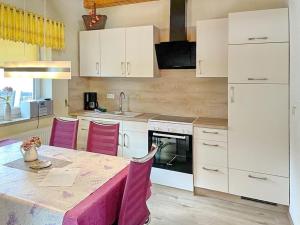 a kitchen with white cabinets and a table with pink chairs at Herz in Lübbenau