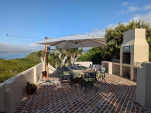a patio with a table and chairs under an umbrella at Villa Cape Garden Route in Wilderness