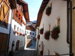 an alley in an old town with flowers on the buildings at Gasthof Gemse in Planol