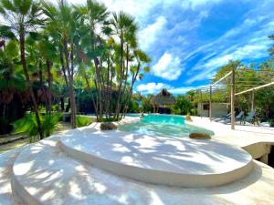 a swimming pool in a yard with palm trees at Muluk Grove Lodge in Placencia