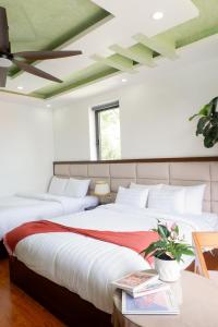 two beds in a bedroom with a green ceiling at Tasme Dalat Stay in Da Lat