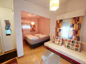 a small room with two beds and a chair at Hôtel Garni Inter-Alp in Saint-Maurice