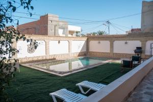 a backyard with two chairs and a swimming pool at Dar Gamra in Tozeur