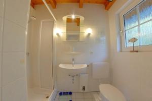 a white bathroom with a toilet and a sink at SV2 Opi-Huck-Stroot 37 in Dorum-Neufeld +6 photos