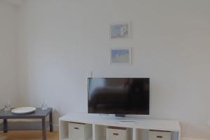 a living room with a tv and a white table at NS 6 Strandläufer Wremen in Wremen +4 photos